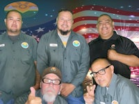 a group of men posing in front of an american flag