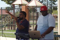 two men standing in front of a fence