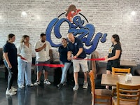 a group of people cutting a ribbon at a restaurant